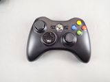 a black game controller sitting on a table next to a keyboard