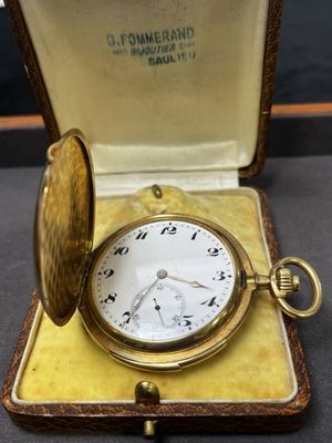 une montre de poche en or dans un écrin posé sur une table
