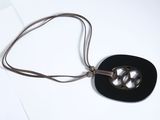 un collier composé d'un disque noir monté sur un cordon marron
