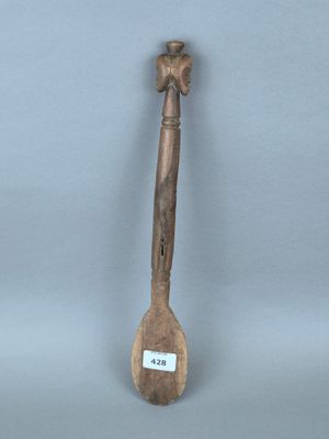 une vieille cuillère en bois posée sur une table, près d'un mur gris