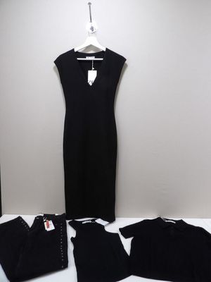La robe noire se trouve à côté d'un pantalon noir et d'une paire de chaussures noires