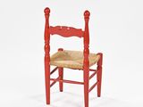 a red wooden chair with a woven seat on a white background