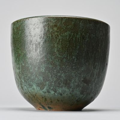 a close up of a green bowl on a white surface