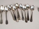six silver spoons are lined up in a row on a white surface