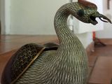 a bird figurine sitting on a tile floor next to a wall