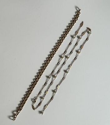 three different chains of silver and gold on a white surface