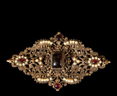 a close up of a gold broochle with pearls and garnets