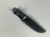 a close up of a knife on a white surface with a black handle