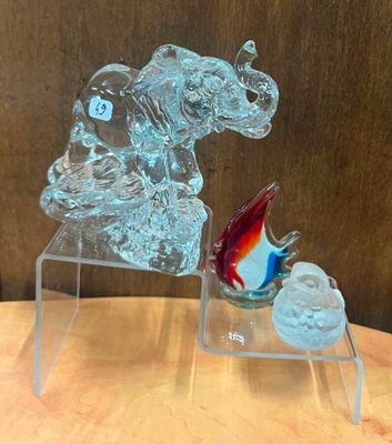 une sculpture en verre représentant un chien et un poisson, posée sur une table
