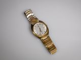 une image d'une montre-bracelet en or sur une surface blanche