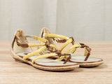 yellow and brown sandals on a wooden table with a curtain in the background
