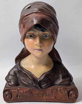 statue of a woman wearing a brown hat and a brown jacket