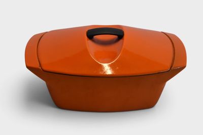 an orange casserole dish with a black handle on a white background