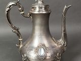 an antique silver tea pot with a bird on top of it