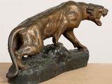 bronze statue of a lion on a rock on a table