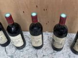 six bouteilles de vin sont alignées sur un plan de travail