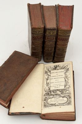 several old books sitting on top of each other on a white surface