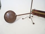 an old fashioned tea strainer on a stand next to an old fashioned tea strainer