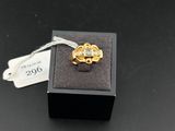 une bague en or ornée d'une fleur, posée sur un coffret noir