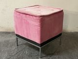 a small pink ottoman sitting on a metal stand