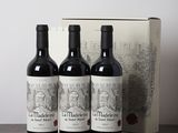 trois bouteilles de vin posées sur une table, à côté d'une boîte