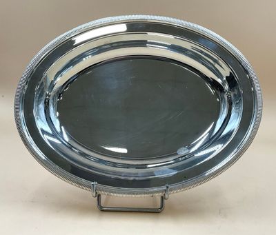 un plateau en argent posé sur un support, sur une table, avec un fond blanc