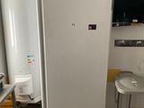un réfrigérateur blanc dans une cuisine où une télévision est accrochée au mur