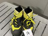 une paire de baskets noires et jaunes, avec des lacets jaunes, posée sur une table en bois