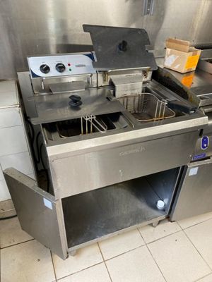 plan de travail en acier inoxydable équipé de deux friteuses dans une cuisine professionnelle