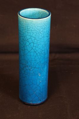 un gros plan d'un vase bleu sur un fond marron