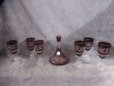 six wine glasses and a decanter sitting on a table