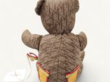 a teddy bear that is sitting on the ground with a tag