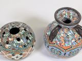 two vases sitting next to each other on a white surface