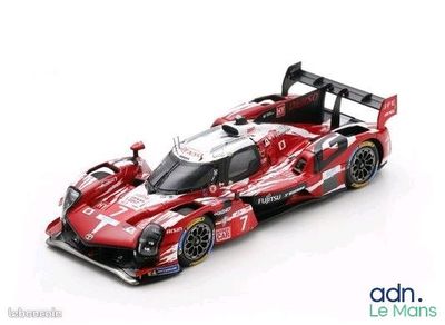 La voiture de course rouge et blanche se trouve sur une surface blanche.