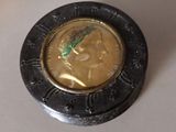 une pièce de monnaie sur laquelle est représenté un visage, posée sur une table