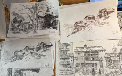 Plusieurs croquis de bâtiments et d'une église sont posés sur une table