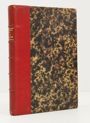 un vieux livre posé sur une table blanche à côté d'un livre rouge