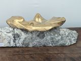 a gold leaf on a rock on a wooden table