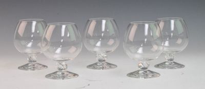 four empty wine glasses are lined up on a white surface