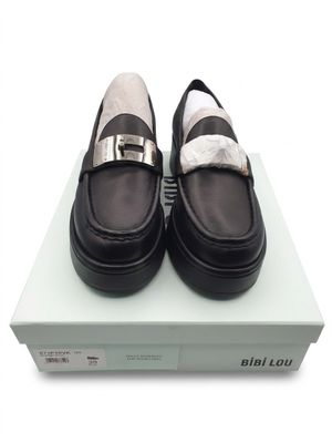 des mocassins noirs et blancs posés sur une boîte, sur une surface blanche