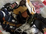 many pairs of shoes in a basket on a bed