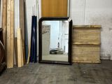 a large mirror sitting in the middle of a room next to a pile of wood