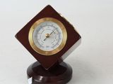 a small clock that is on a stand on a white surface