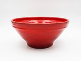 a red bowl that is sitting on a white surface