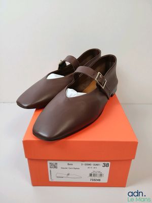 des chaussures en cuir marron avec des boucles, posées sur une boîte orange