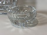a small glass bowl sitting on a table next to a small glass candle holder