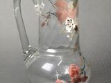 a clear glass pitcher with a floral design on it