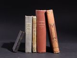 three old books are stacked on top of each other on a black surface
