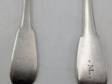 two spoons that are sitting next to each other on a table