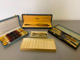 several pens and pencils are sitting in a case on a table